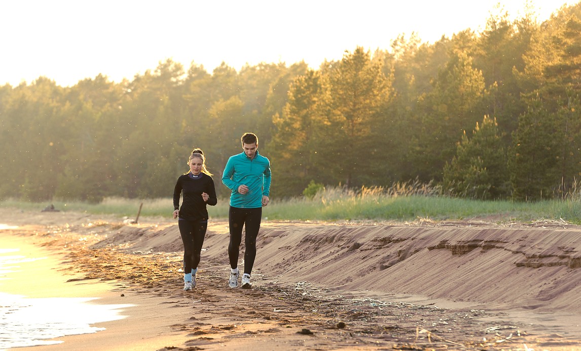 To personer løber en tur langs med vandet på strand