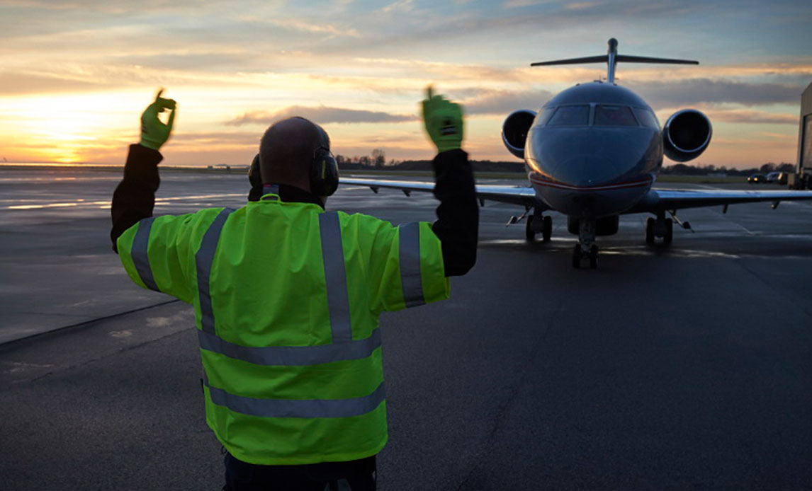 Mand i refleksvest og med høreværn guider challengerfly på landsbane.