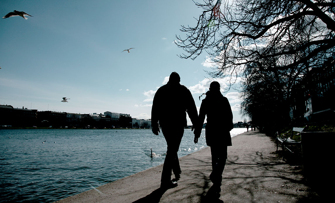Et par går tur hånd i hånd ved søerne i København.