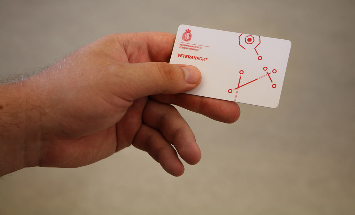 Mandehånd, der holder et hvidt plastikkort i stil med et dankort. Teksten på kortet siger Veterankort.