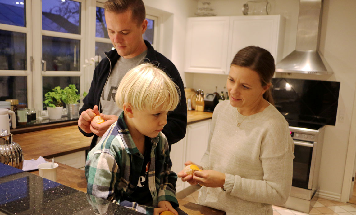 Mor, far og barn er samlet i køkkenet.