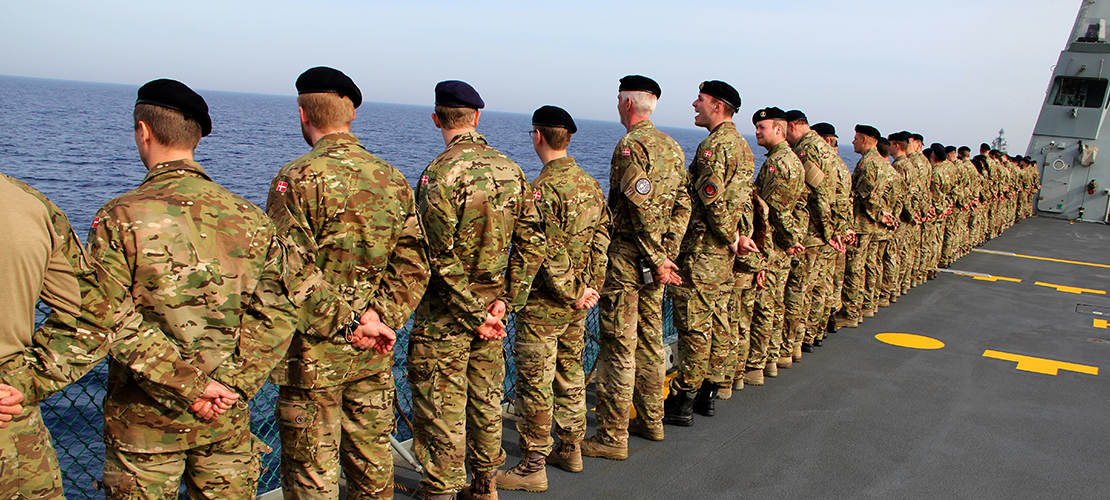 Soldater står med ryggen til ved rælingen på et af Forsvarets grå skibe.