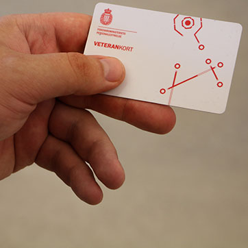 Mandehånd, der holder et hvidt plastikkort i stil med et dankort. Teksten på kortet siger Veterankort.