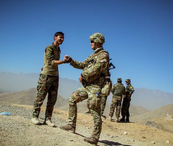 Dansk soldat giver hånd til afghansk soldat.