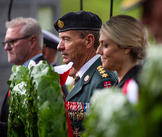 Flagparade med adskillige danske faner og enkelte blå NATO-faner. Fanebærerne ses gå gennem Aalborg midtby.